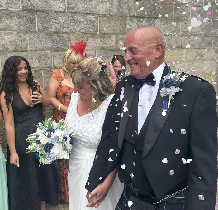 real life bride and groom with artificial navy and dusty blue flowers by the brides bouquet