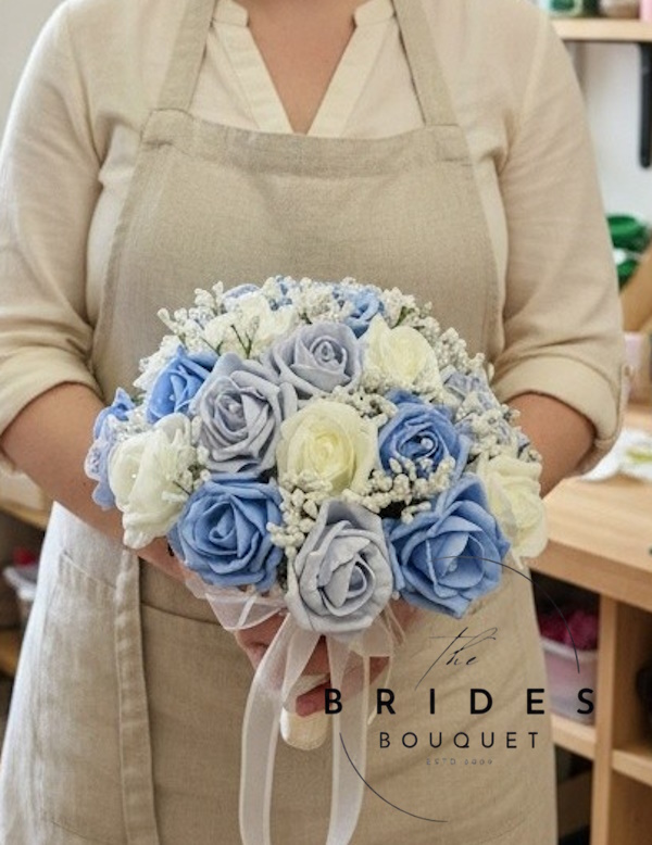 florist holding dusty blue and light blue rose wedding bouquet with lots of gyp
