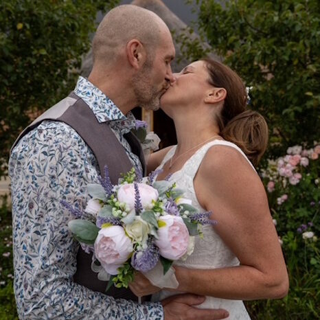 real life bride and groom kissing with silk peony and heather bridal bouquet