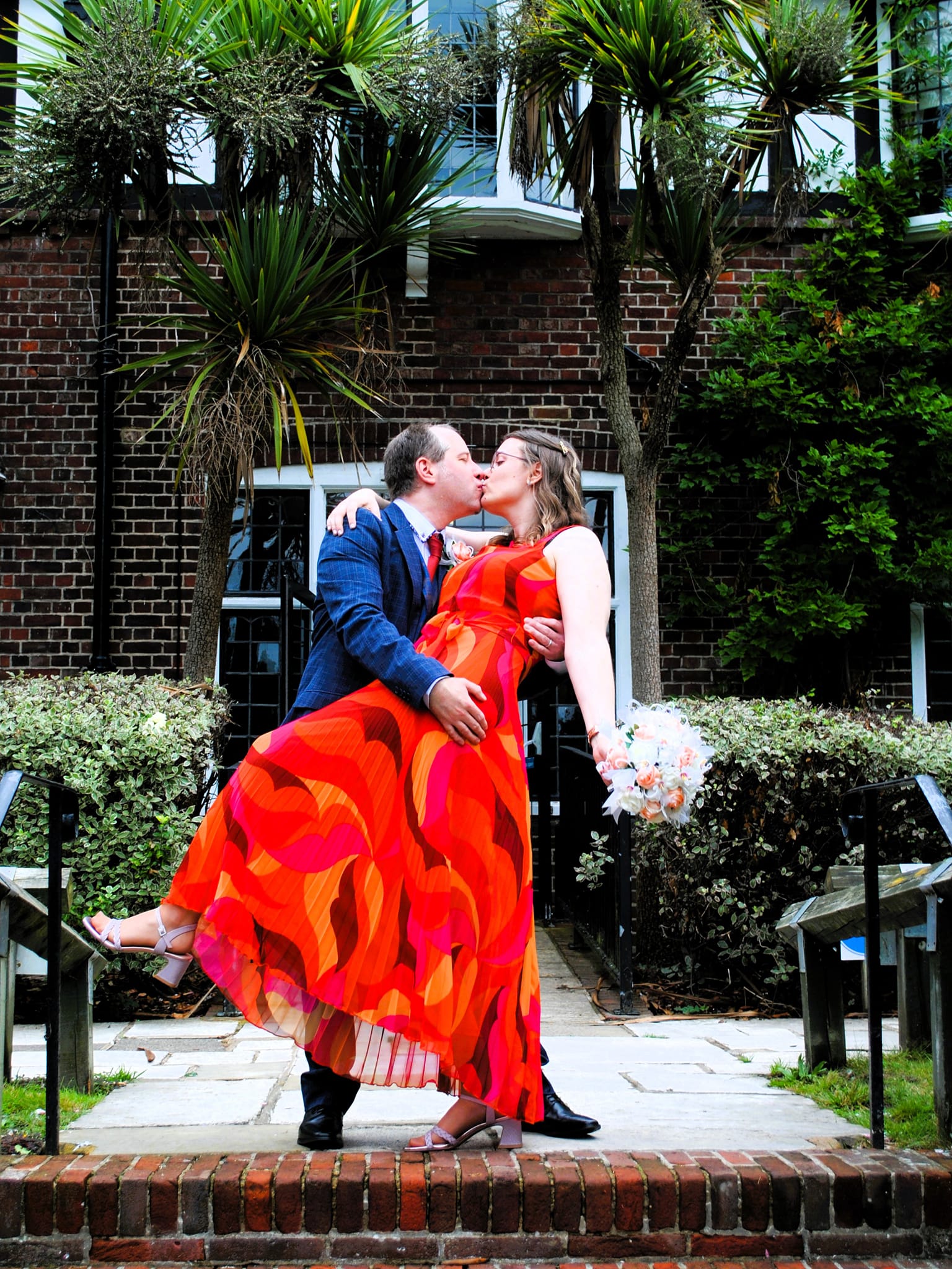 bride and groom kissing with artificial flowers created by the brides bouquet uk