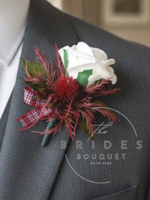 Thistle and rose wedding buttonhole in burgundy and red with artificial eryngium thistle and ribbon bow
