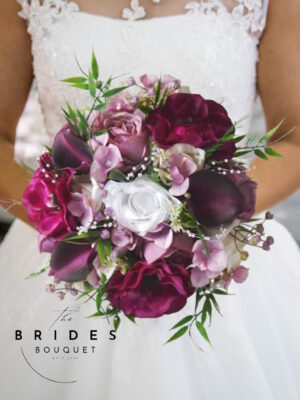 Jewelled tone silk bridal bouquet in magenta, mauve, and white with anemone, roses, calla lily, hydrangea, pearl loops, and partially wrapped handle